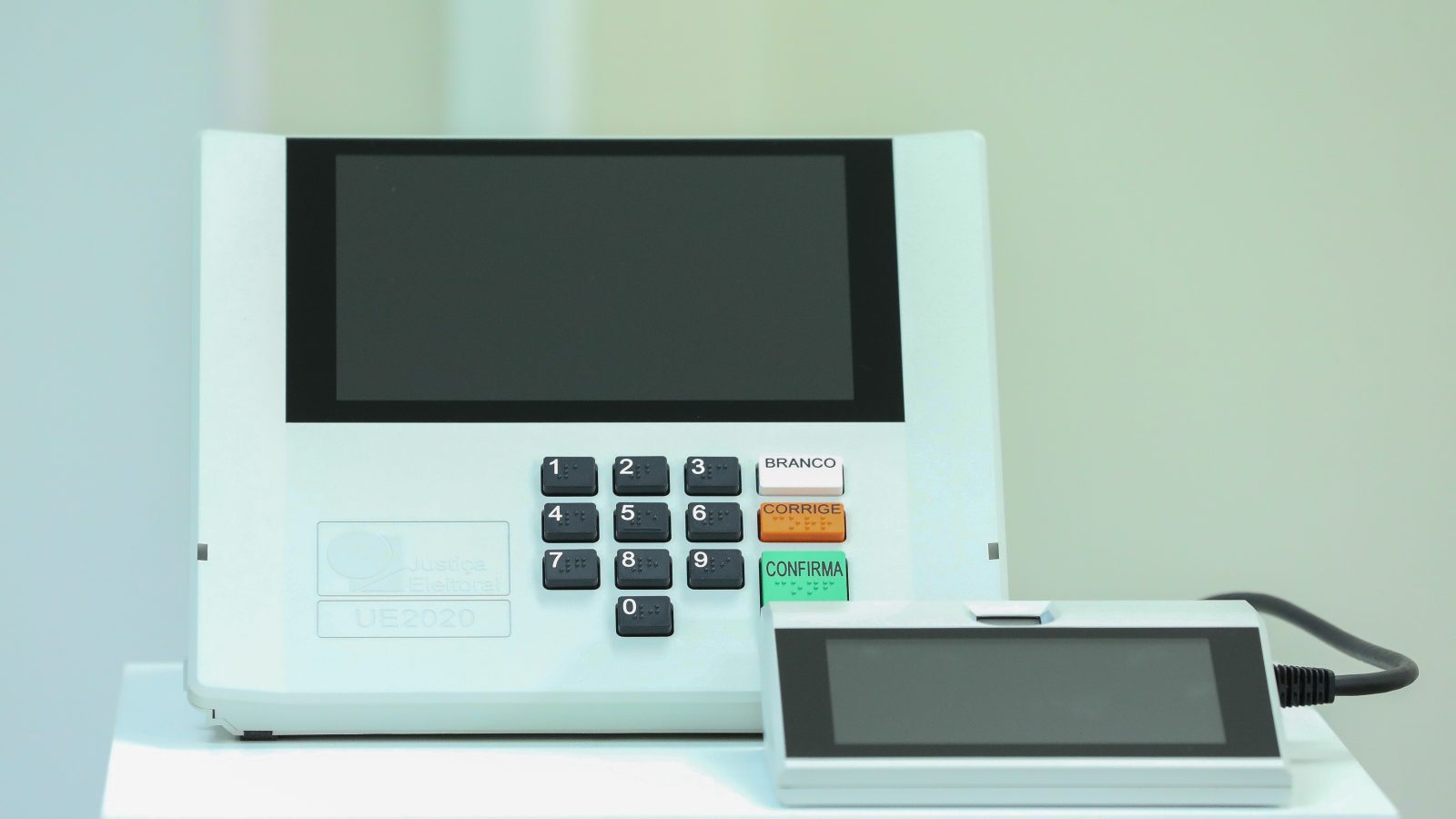 Urna eletrônica modelo UE2020 com terminal do mesário ao lado, aparelho da Justiça Eleitoral