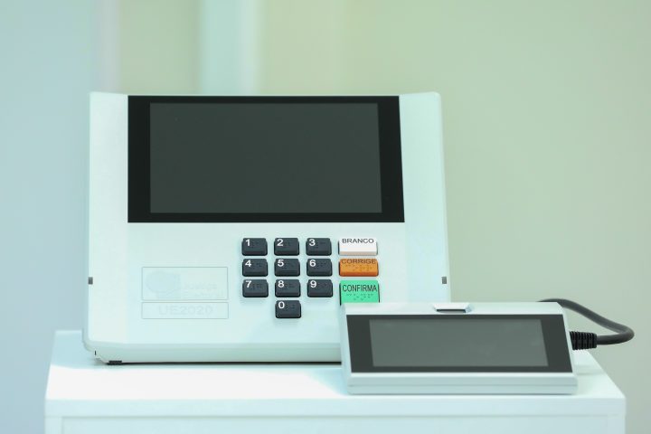 Urna eletrônica modelo UE2020 com terminal do mesário ao lado, aparelho da Justiça Eleitoral
