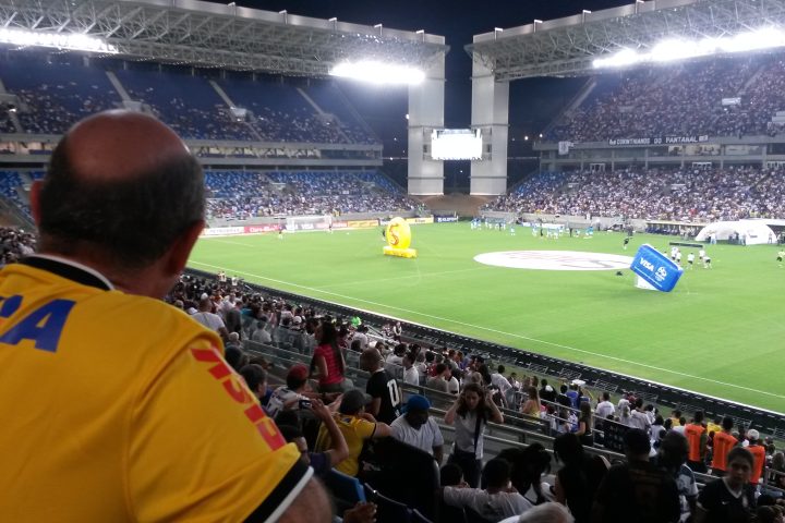 Vista interna da Arena Pantanal, em Cuiabá (MT), com torcida e gramado durante partida.