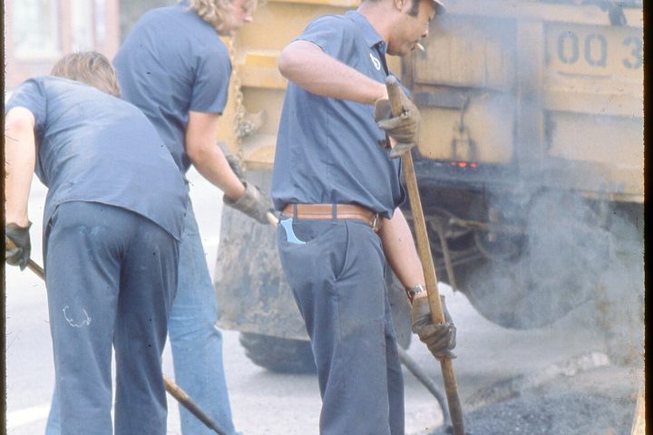 Trabalhadores aplicando asfalto em obra de pavimentação