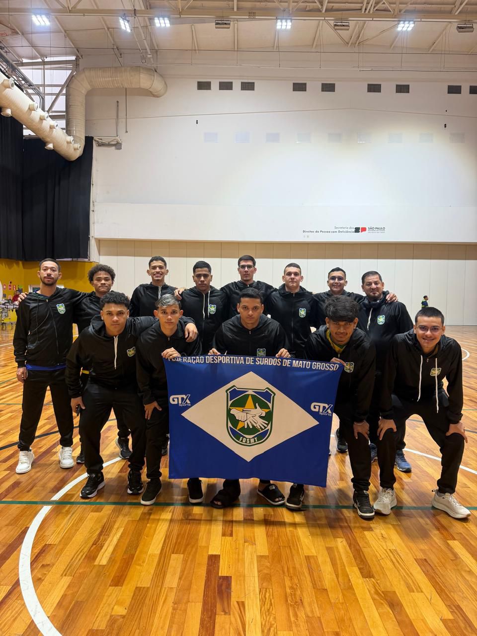 Atletas da Federação Desportiva de Surdos de Mato Grosso posam com a bandeira da FDSMT