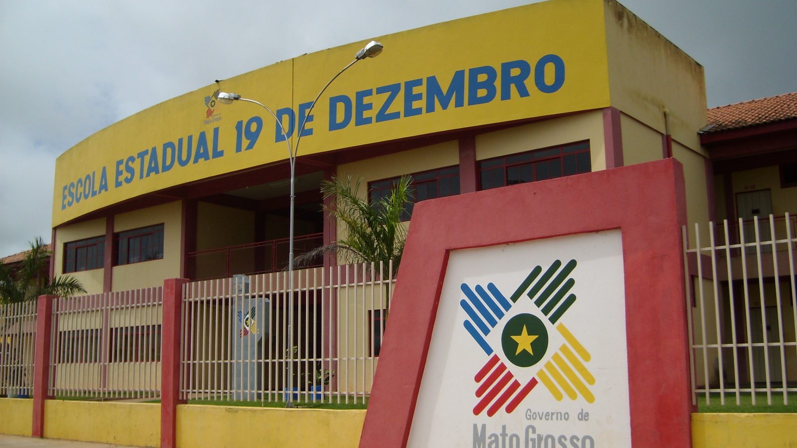 Fachada de escola pública em Mato Grosso com o brasão do Estado