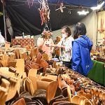 Pessoas visitam banca de artesanato em feira