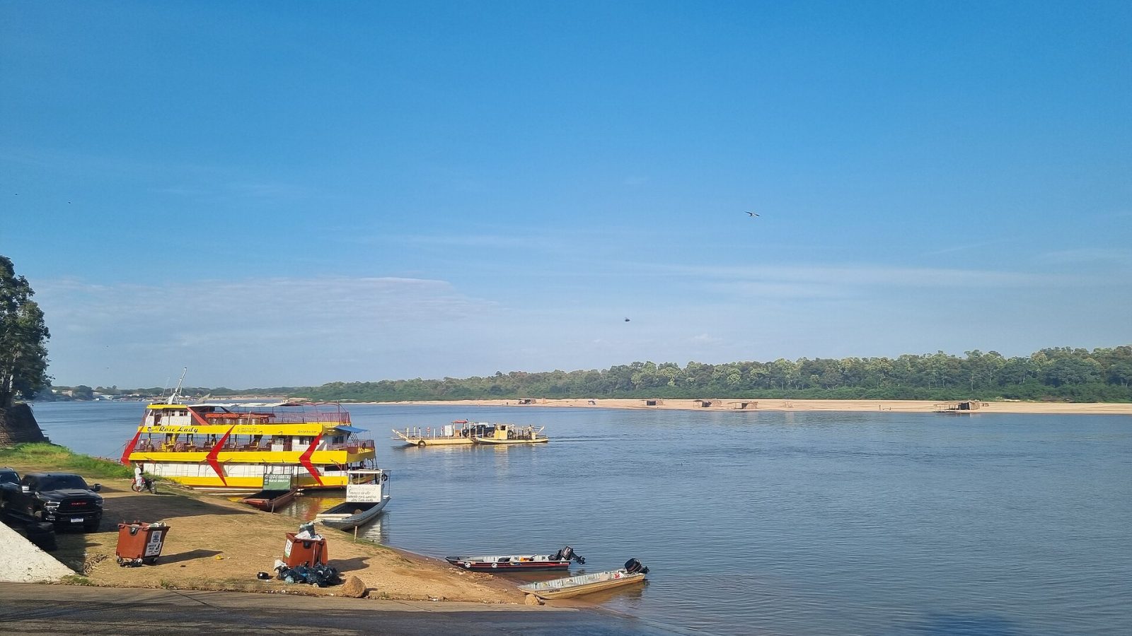 Praia às margens de rio com embarcações