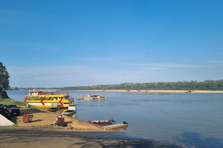 Praia às margens de rio com embarcações