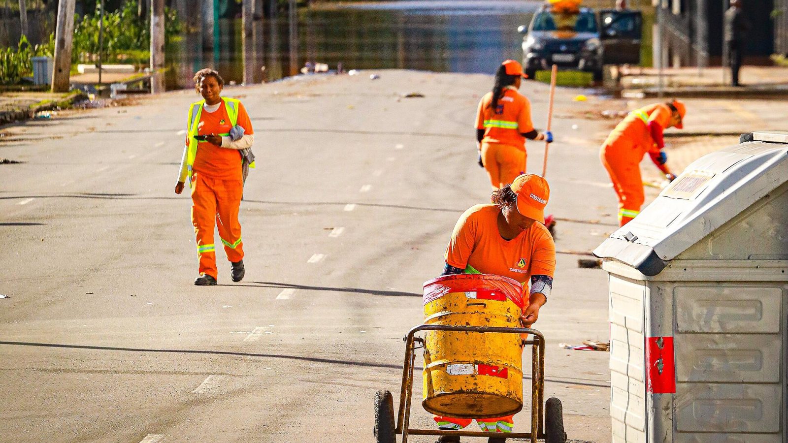 Trabalhadores da limpeza urbana com uniforme laranja em via pública
