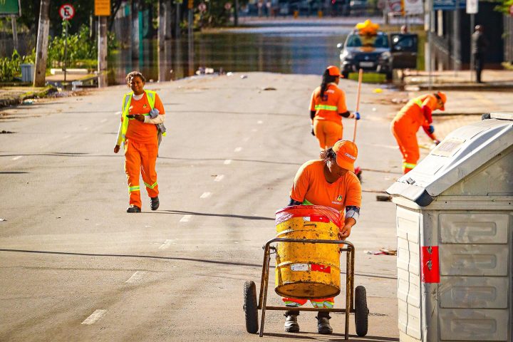 Trabalhadores da limpeza urbana com uniforme laranja em via pública
