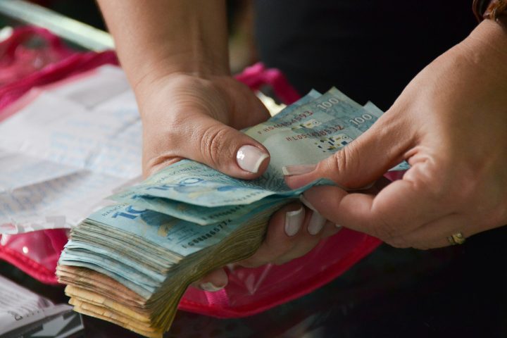 Mãos contando cédulas de real