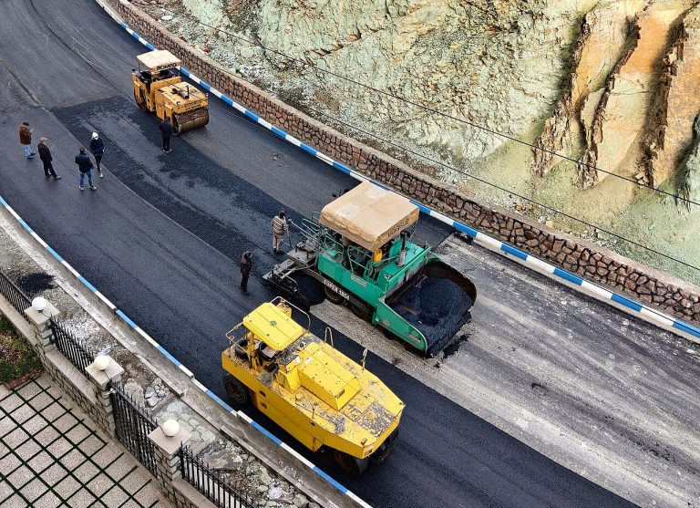 Máquinas de pavimentação aplicando asfalto em via urbana