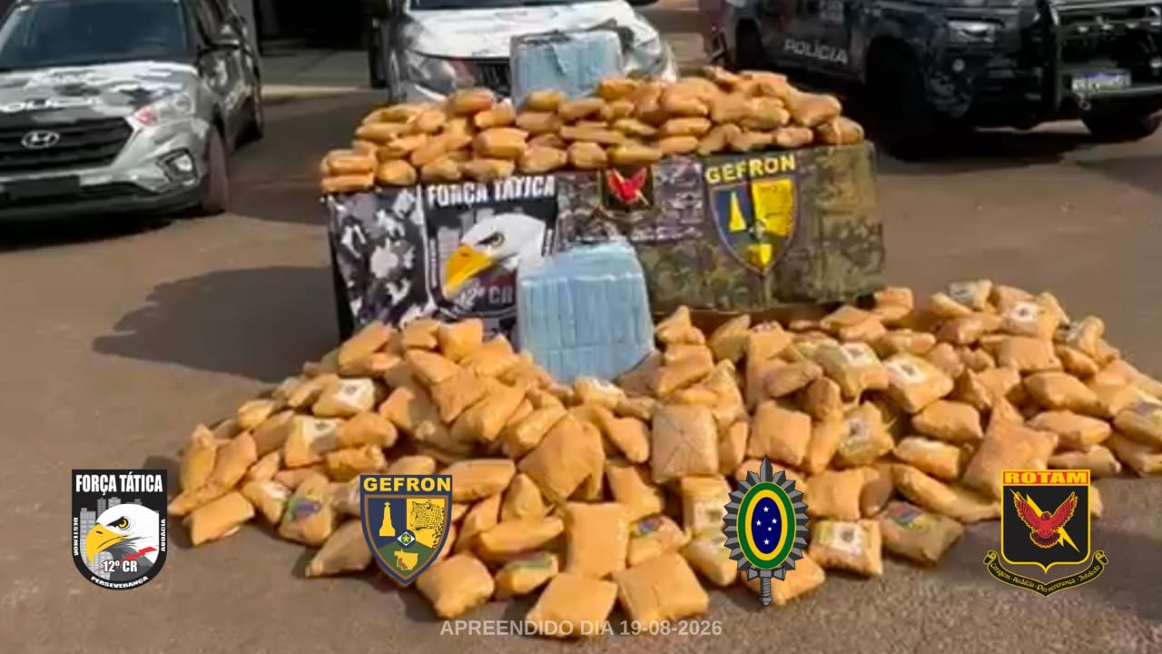 Tabletes de skunk empilhados no pátio, com viaturas policiais ao fundo