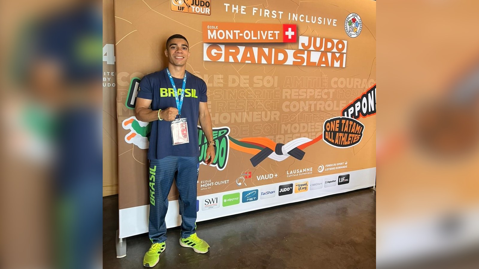 Judoca Pedro Dantas, de camiseta do Brasil, posa diante do painel do École Mont-Olivet Lausanne Grand Slam