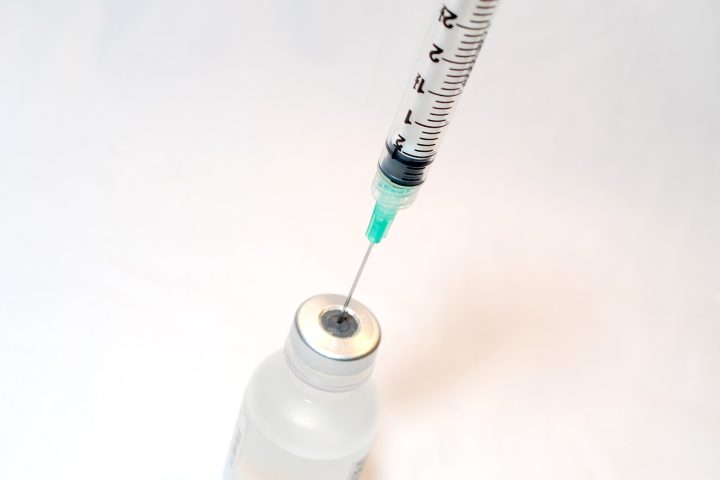 Seringa com agulha inserida em frasco de vacina