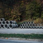 Tubos de concreto empilhados à beira de uma estrada de cascalho