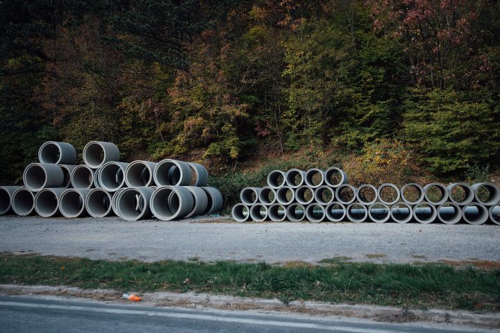 Tubos de concreto empilhados à beira de uma estrada de cascalho