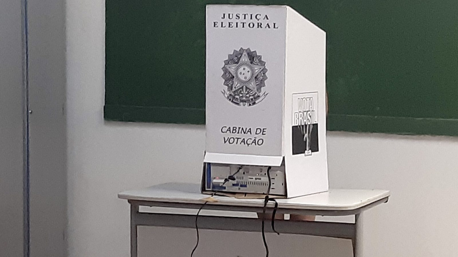 Cabine de votação da Justiça Eleitoral montada sobre mesa em seção eleitoral, sem eleitores