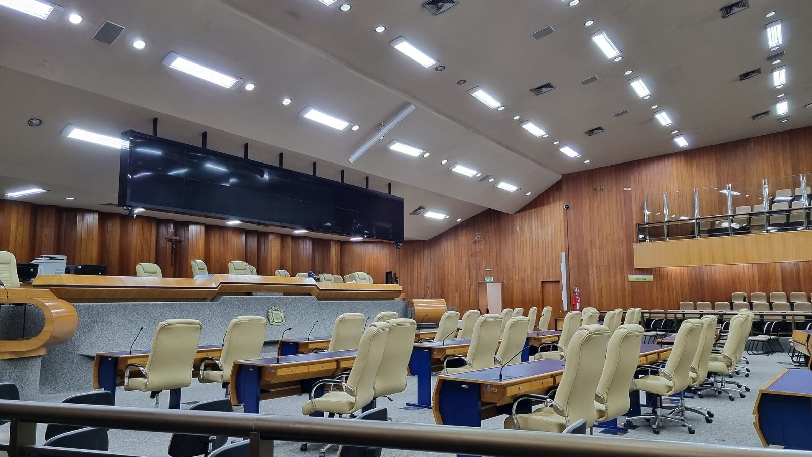 Plenário vazio de uma câmara municipal, com bancadas e cadeiras dos vereadores