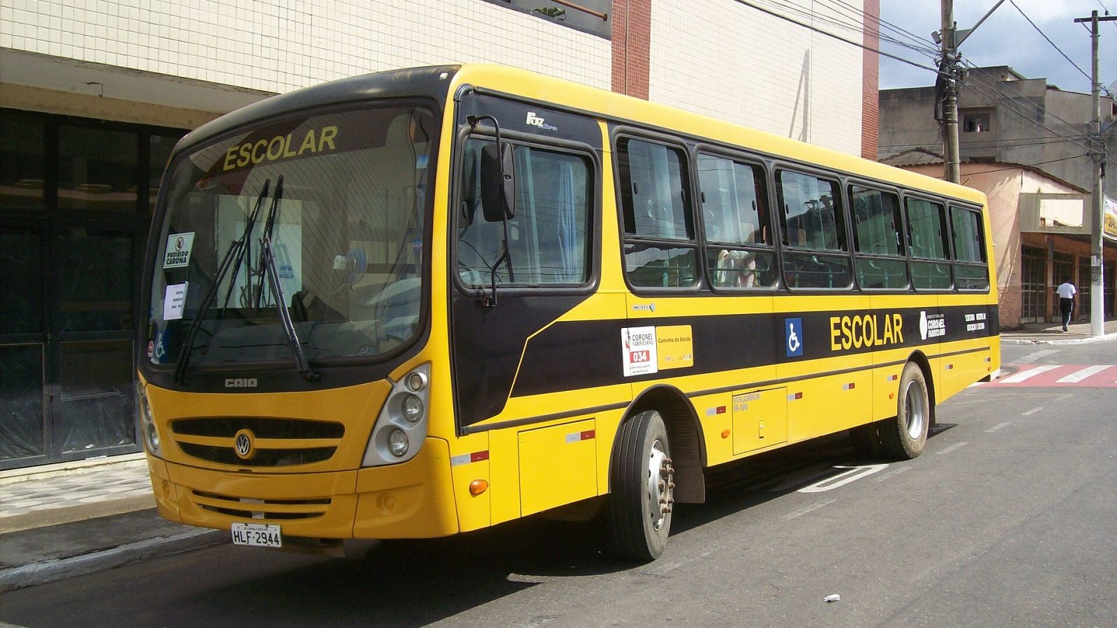 Ônibus escolar amarelo com a inscrição Escolar estacionado em via urbana