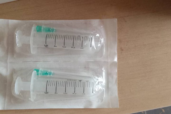 Duas seringas descartáveis com agulha em embalagens estéreis lacradas