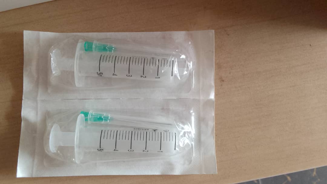 Duas seringas descartáveis com agulha em embalagens estéreis lacradas
