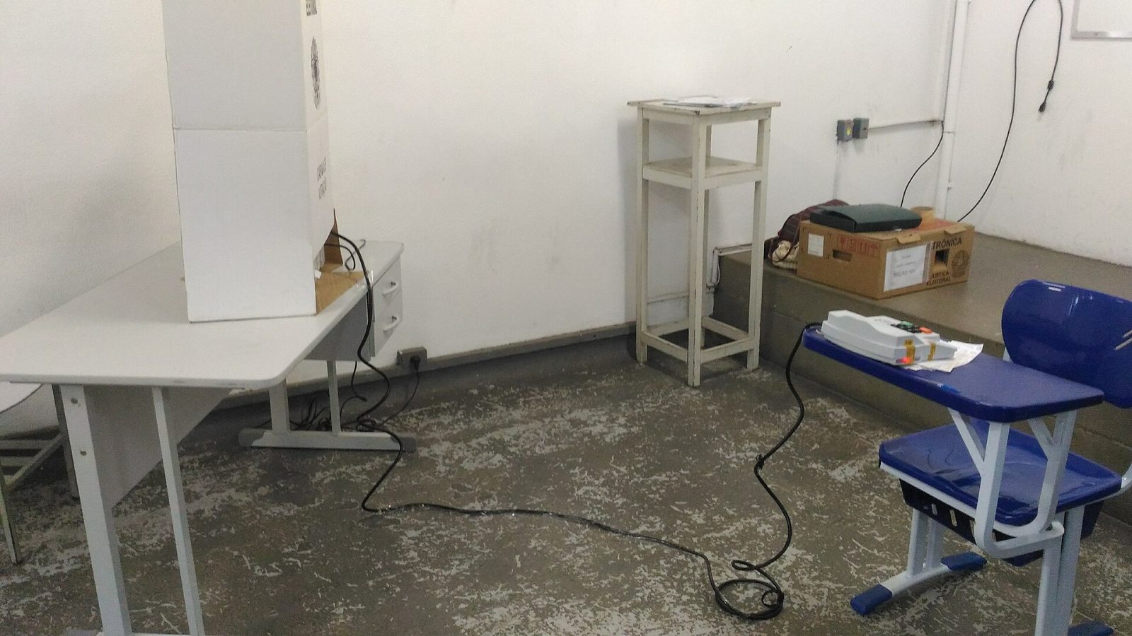 Urna eletrônica e cabine de votação em sala de seção eleitoral